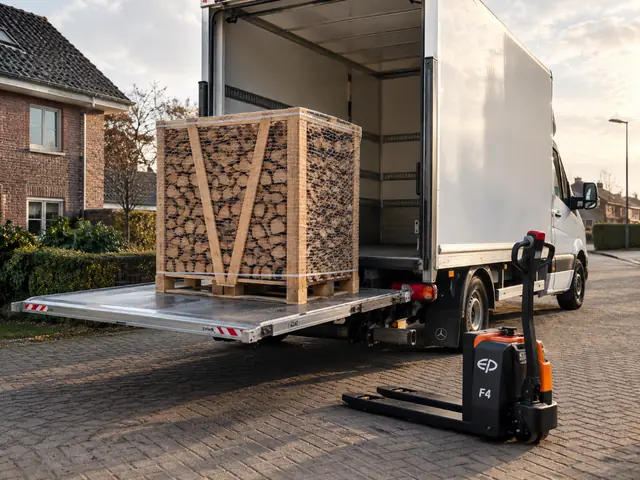 Een pallet haardhout wordt met een laadklep van een bestelbus bezorgd
